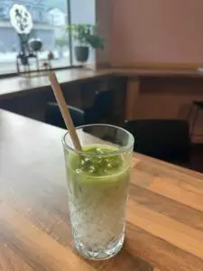 Un verre de matcha au lait avec une paille, posé sur un bar de restaurant.